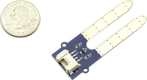 Okrągła, srebrzysta ćwierćdolarówka obok niebieskiego czujnika z dwoma długimi, złotymi sondami do pomiaru wilgotności gleby.