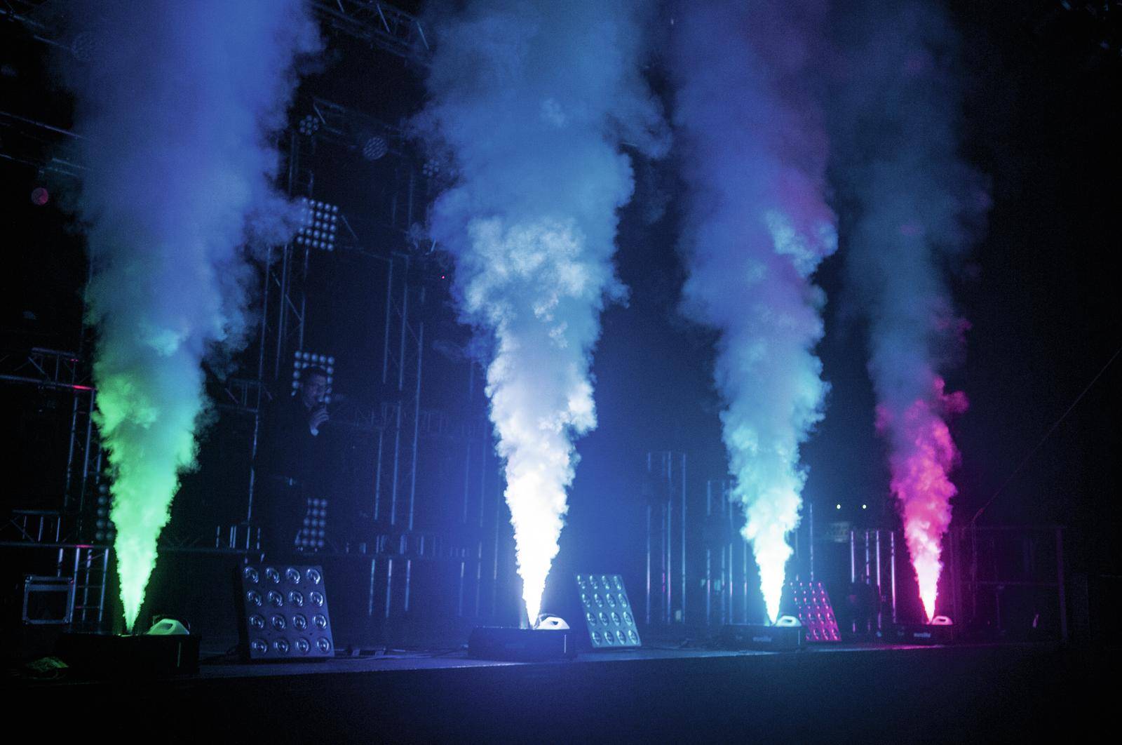 Wielokolorowe efekty świetlne i mgielne na scenie, od lewej do prawej: zielone, niebieskie, fioletowe, różowe. Scena bez osób.