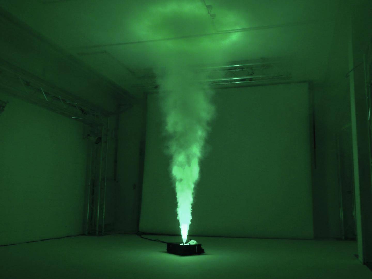 Efekt dymu w ciemnym pomieszczeniu jest podświetlany od dołu na zielono, co tworzy mistyczną i tajemniczą atmosferę.