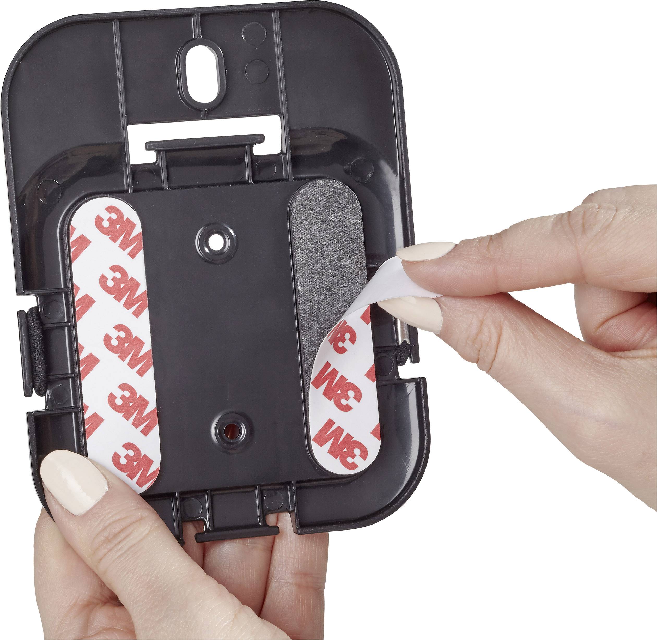 Dwie ręce mocują podkładki samoprzylepne na czarnym uchwycie. Podkładki prezentują czerwone logo 3M.