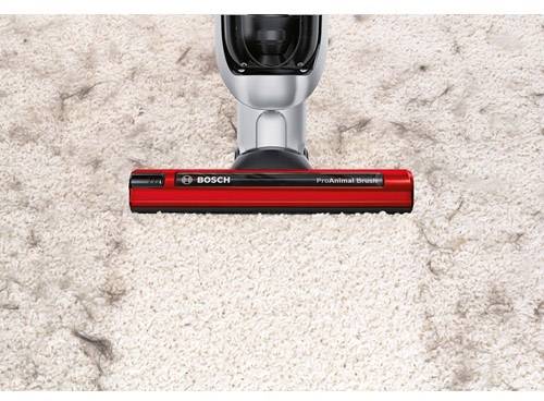 Odkurzacz zbiera sierść zwierzęcia z jasnego dywanu; czerwona szczotka z napisem 'ProAnimal' podkreśla funkcjonalność w usuwaniu sierści zwierząt.