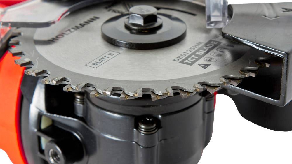Zbliżenie piły tarczowej z wyraźnie ostrymi zębami i solidnym mocowaniem. Na ostrzu widoczna jest marka 'Holzmann'.