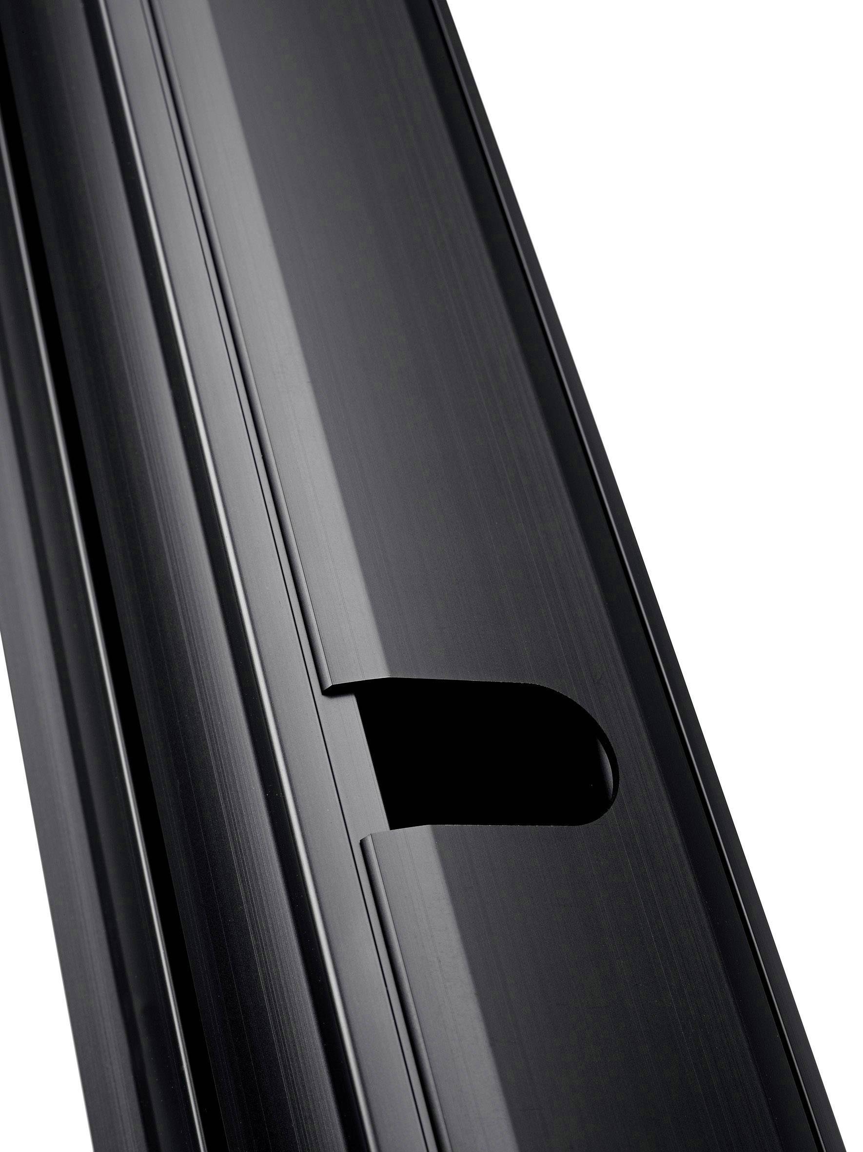 Czarna metalowa powierzchnia z wąskim otworem, która może być częścią urządzenia lub elementu wyposażenia.