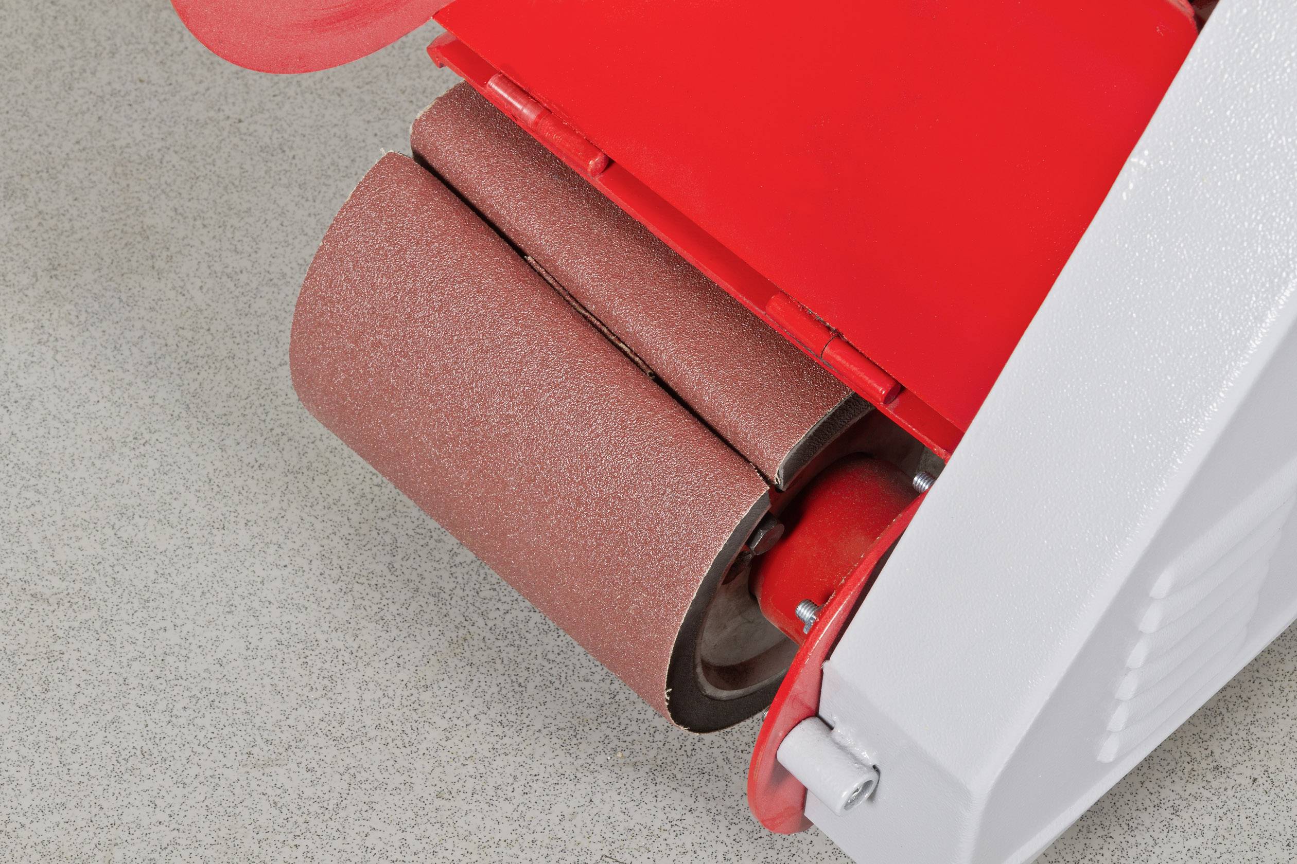 Szlifierka z brązowym papierem ściernym, sfotografowana z bliska. Służy do wygładzania powierzchni, głównie w pracach stolarskich.