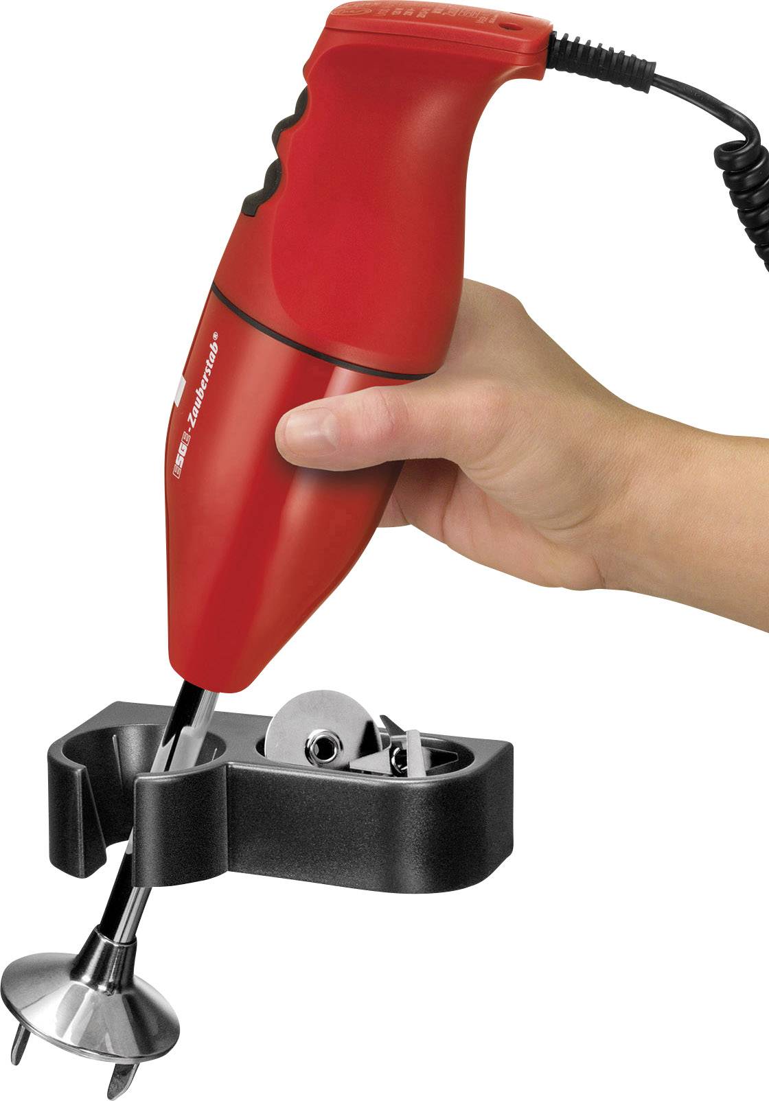 Ręka trzyma czerwony blender ręczny nad czarnym uchwytem. Blender jest podłączony do źródła zasilania.