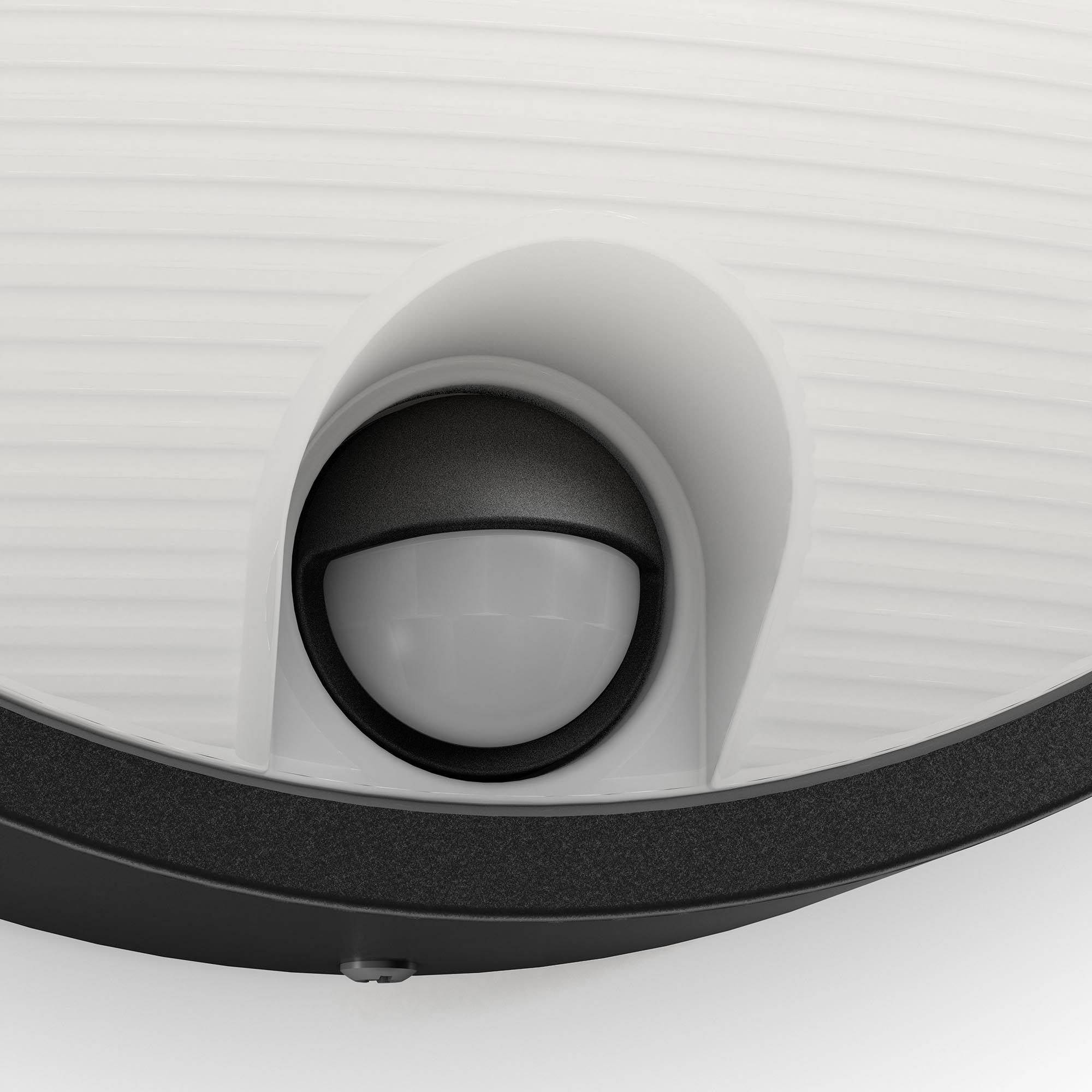 Okrągły, biały czujnik ruchu z małą, czarną osłoną pośrodku, zamontowany na powierzchni.