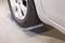 Opona samochodowa spoczywa na srebrnej metalowej pochylni przy podłodze, prawdopodobnie w celu stabilizacji lub naprawy pojazdu.