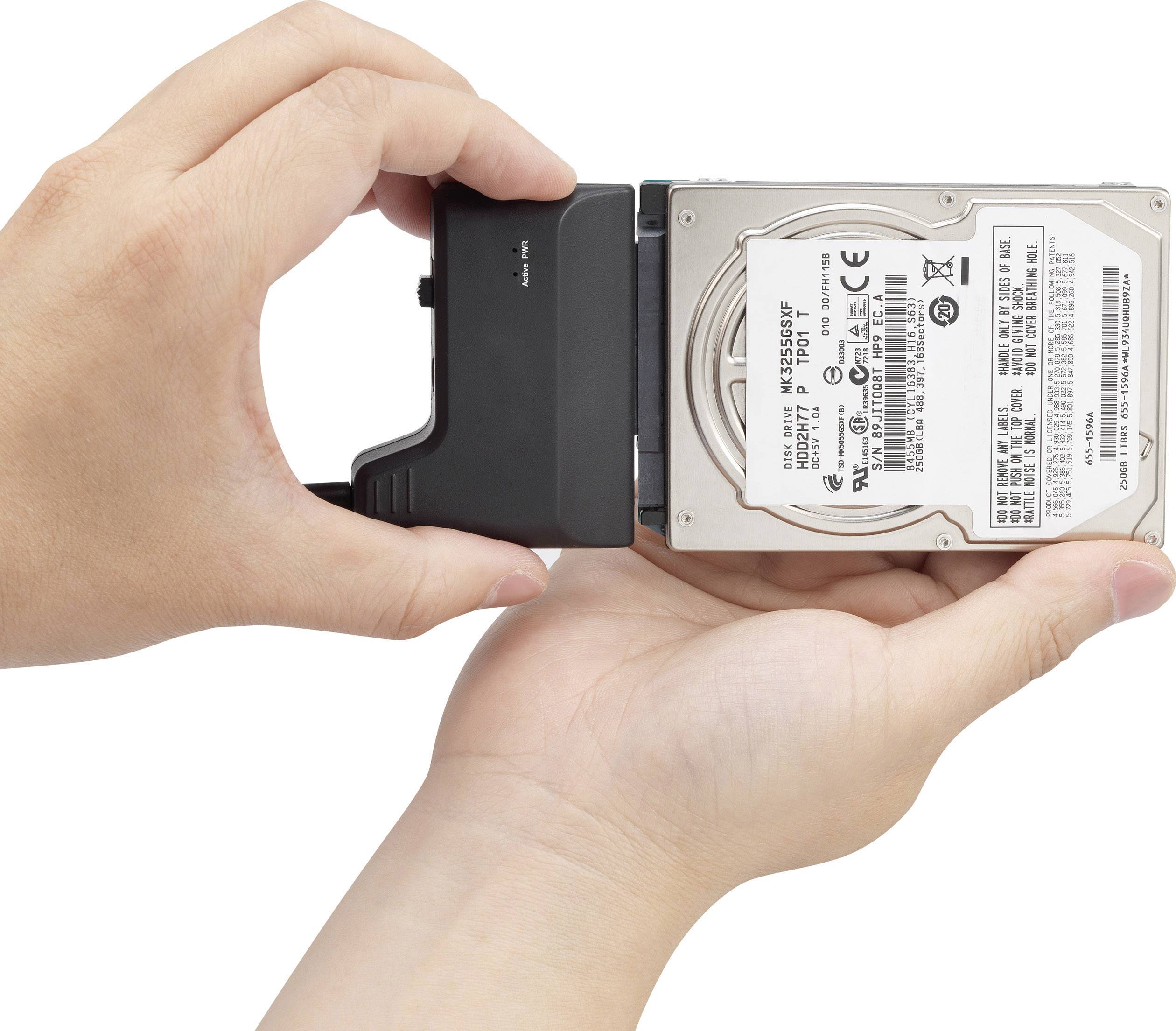 Dwie ręce trzymają stację dokującą do dysków zewnętrznych z podłączoną wewnętrzną dyskietką.