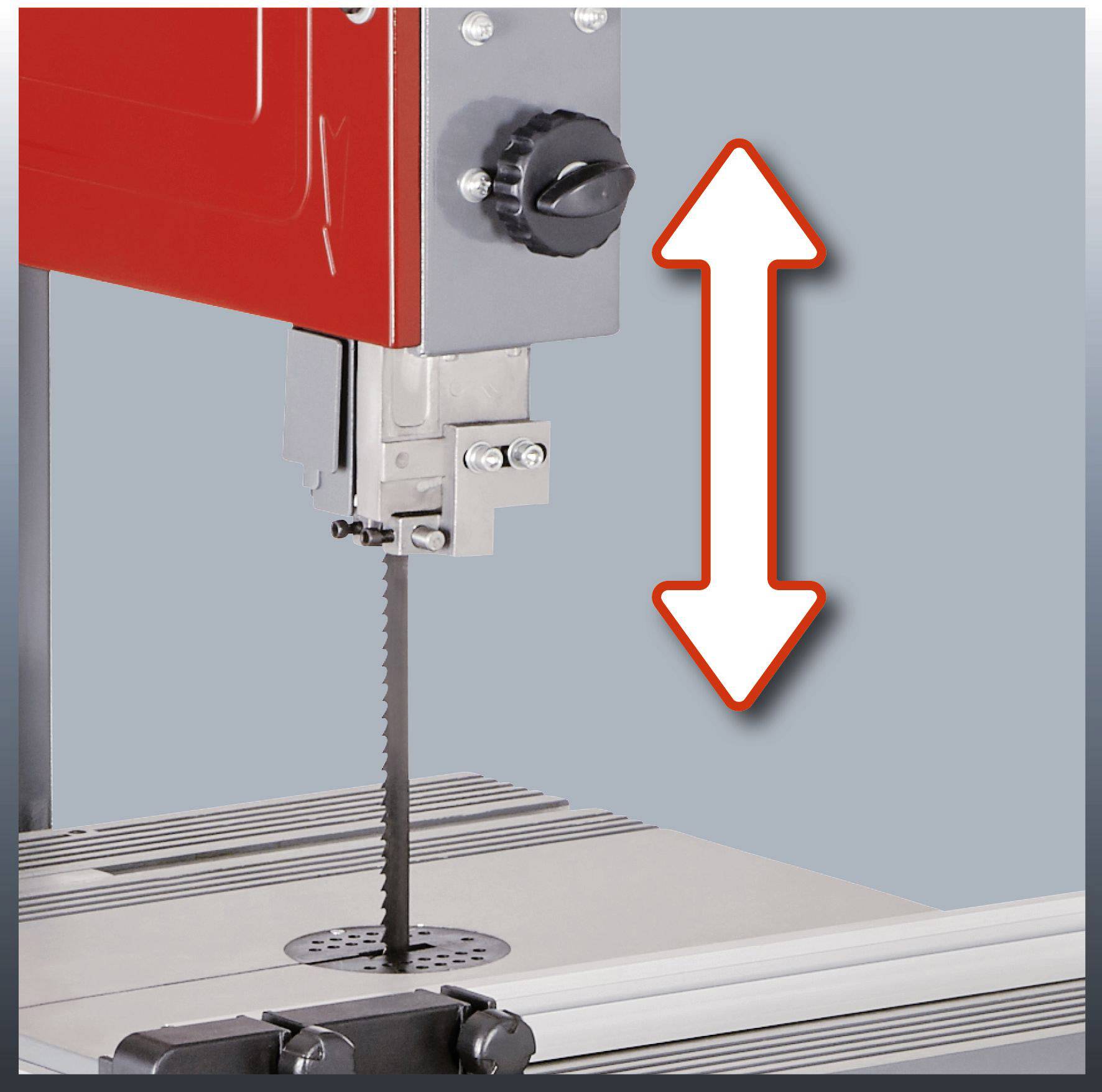 Piła taśmowa z czerwoną obudową, centrowane ostrze piły. Strzałka wskazuje kierunek ruchu piły w górę i w dół.
