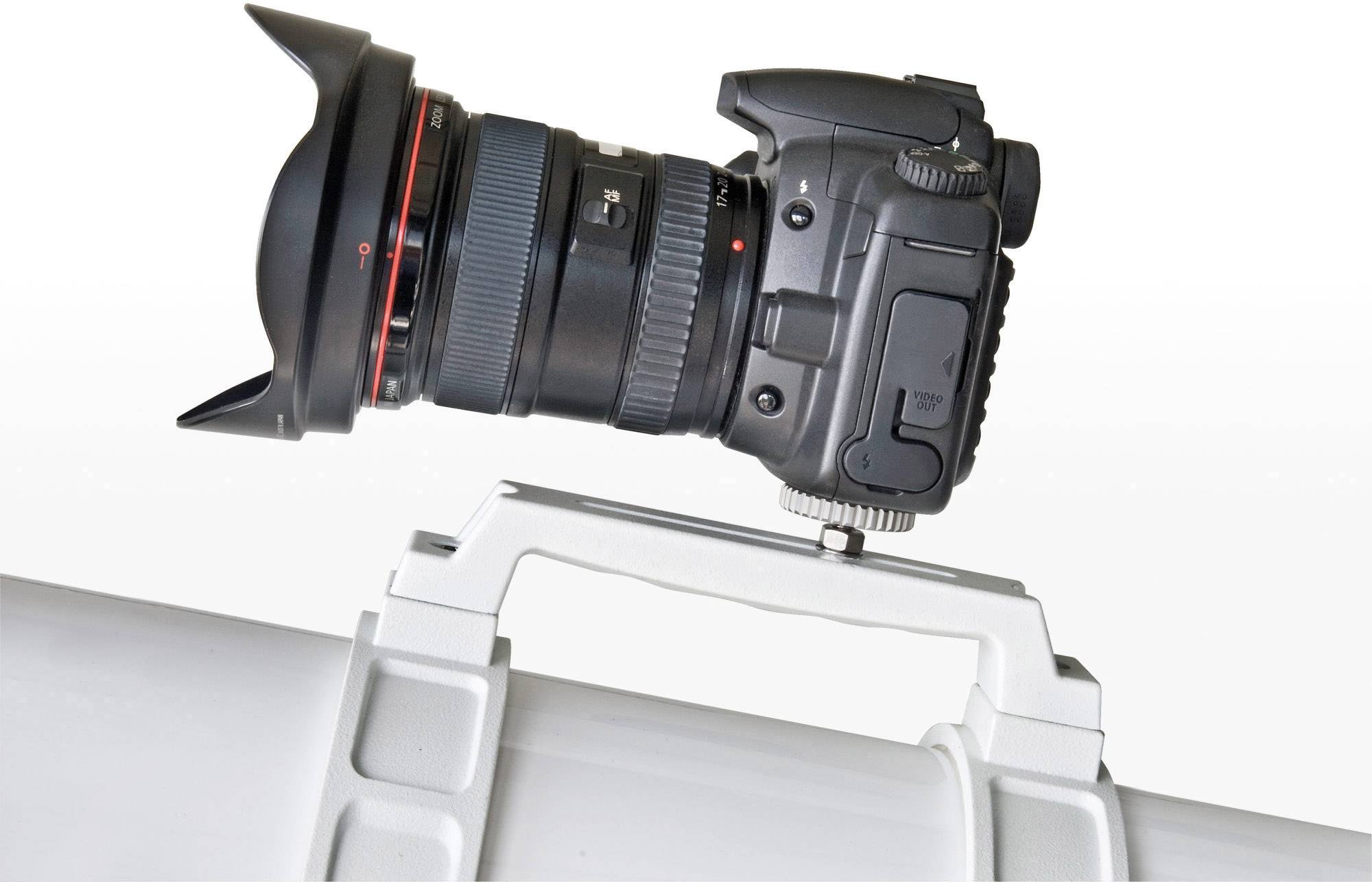 Cyfrowy aparat fotograficzny z zamocowanym obiektywem, przymocowany do białego statywu teleskopowego, widziany z boku.