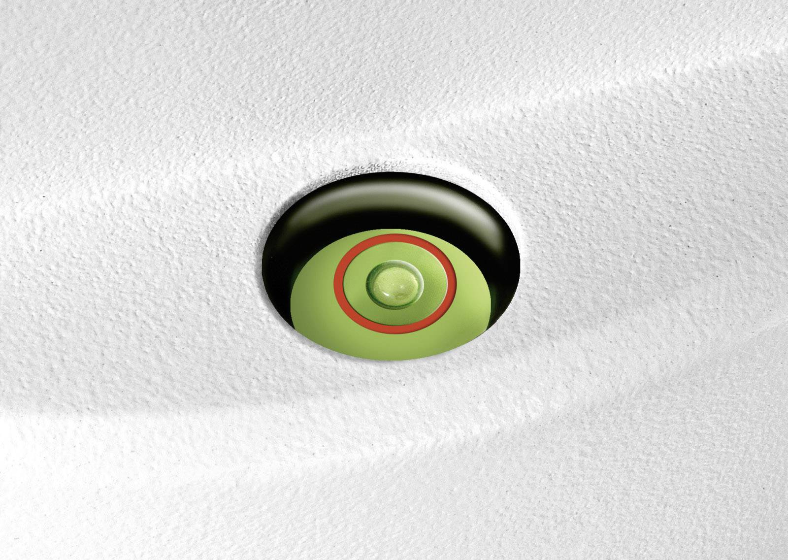 Zielony, okrągły przycisk w białej, strukturyzowanej obudowie. Przycisk otoczony jest czerwonym pierścieniem i jest lekko zagłębiony.