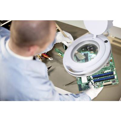 Technik czyści płytkę drukowaną pędzlem pod podświetloną lupą.