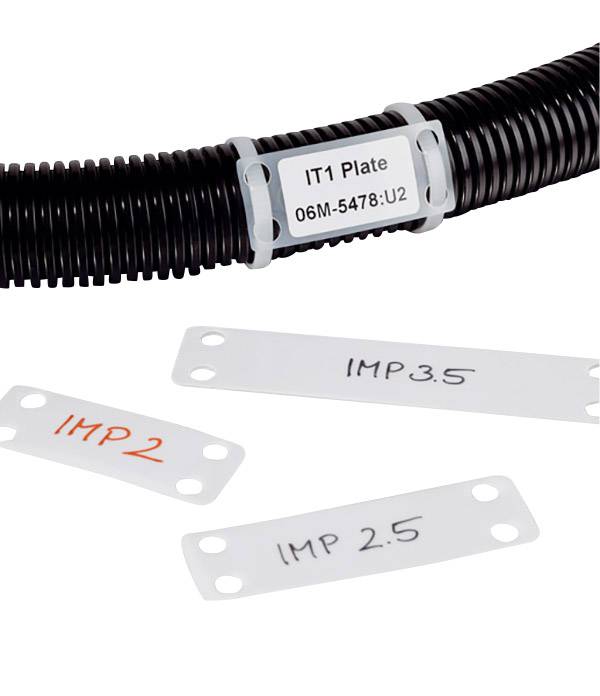 Czarna elastyczna rura z białą etykietą 'IT1 Plate 06M-5478: U2', obok niej trzy białe etykiety z napisami 'IMP 2', 'IMP 2.5' i 'IMP 3.5'.