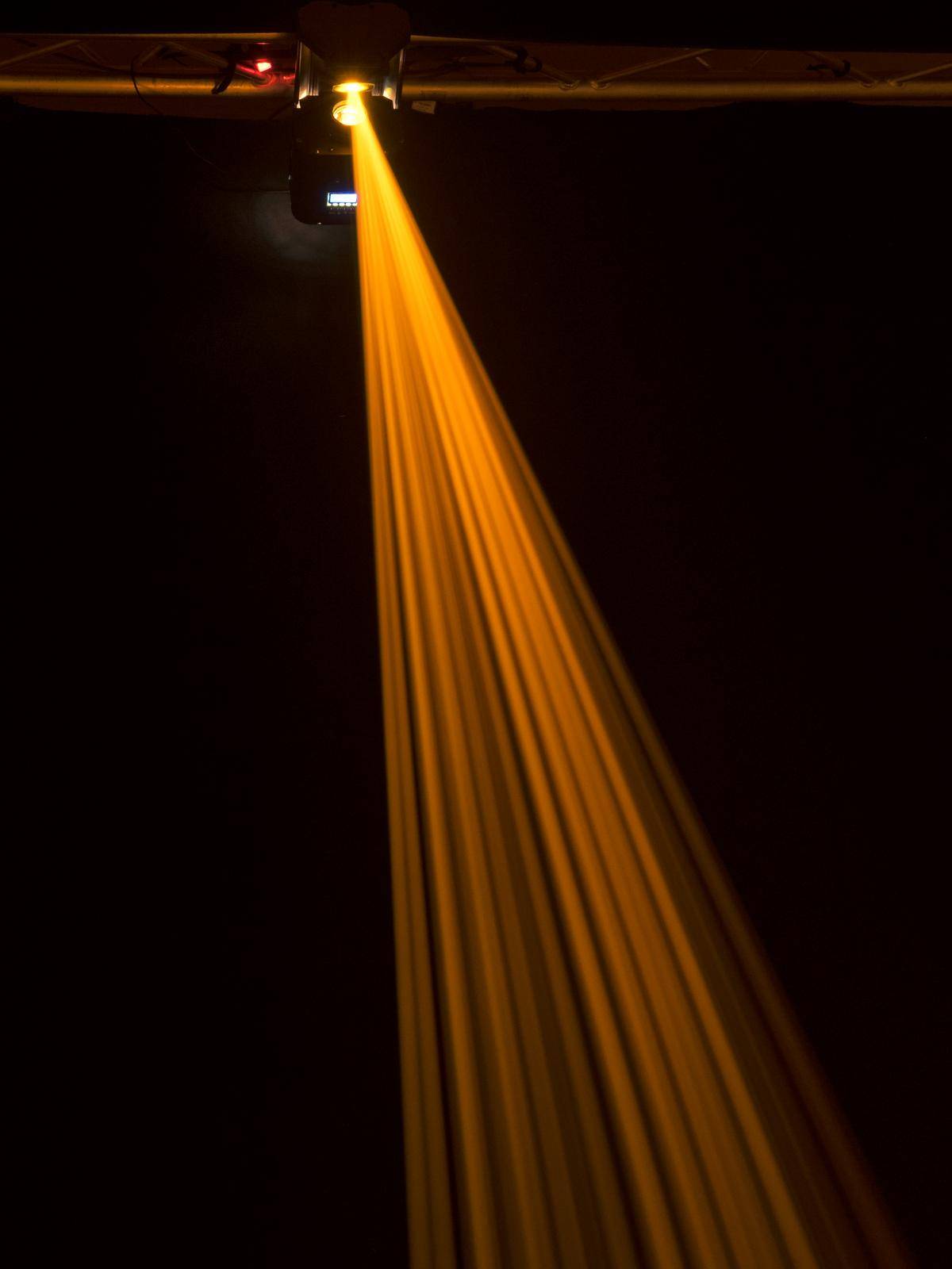 Pojedynczy żółty promień światła spływa z góry w ciemnym pomieszczeniu, tworząc imponujący kontrast między światłem a cieniem.