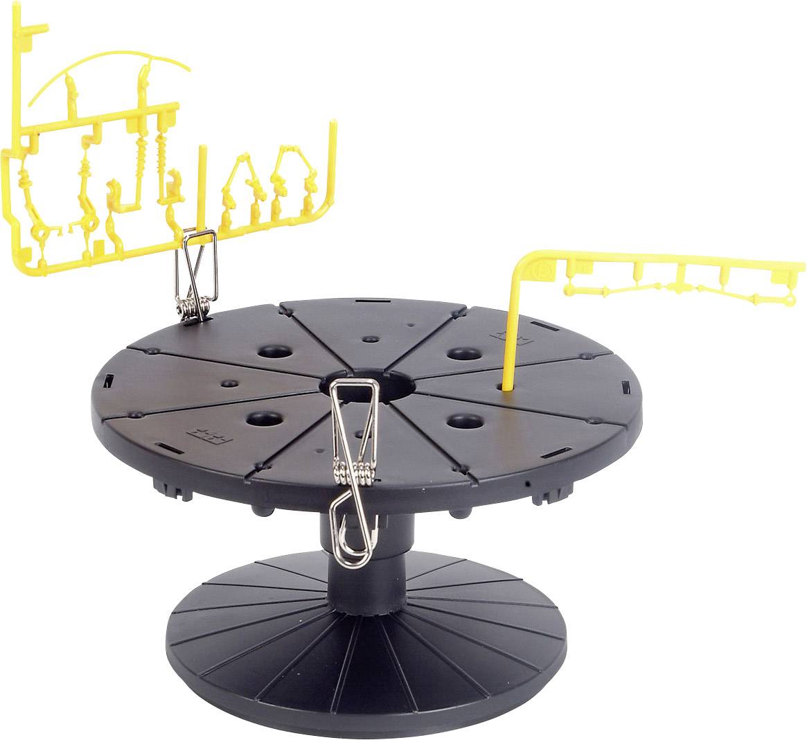 'Czarny, okrągły cokół z zaciskami i żółtymi elementami modelarskimi przymocowanymi do gałęzi. Służy do organizacji elementów modelu.'