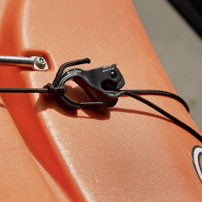 Pomarańczowy kajak z czarną linką mocującą. Linka jest napięta nad hakiem mocującym.