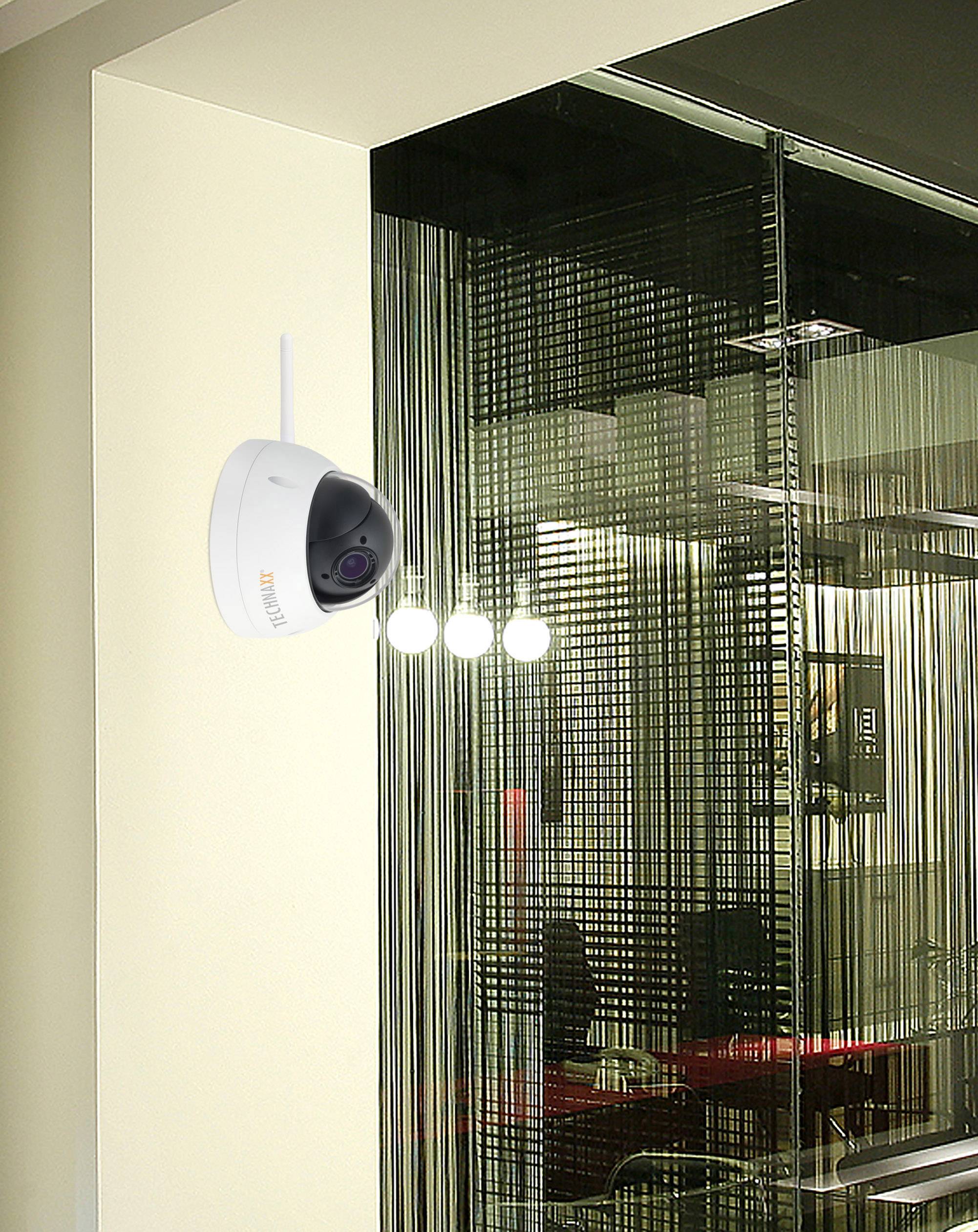 Kamera monitorująca jest zamontowana na ścianie i nadzoruje nowoczesną przestrzeń biurową z przeszklonymi ściankami działowymi.