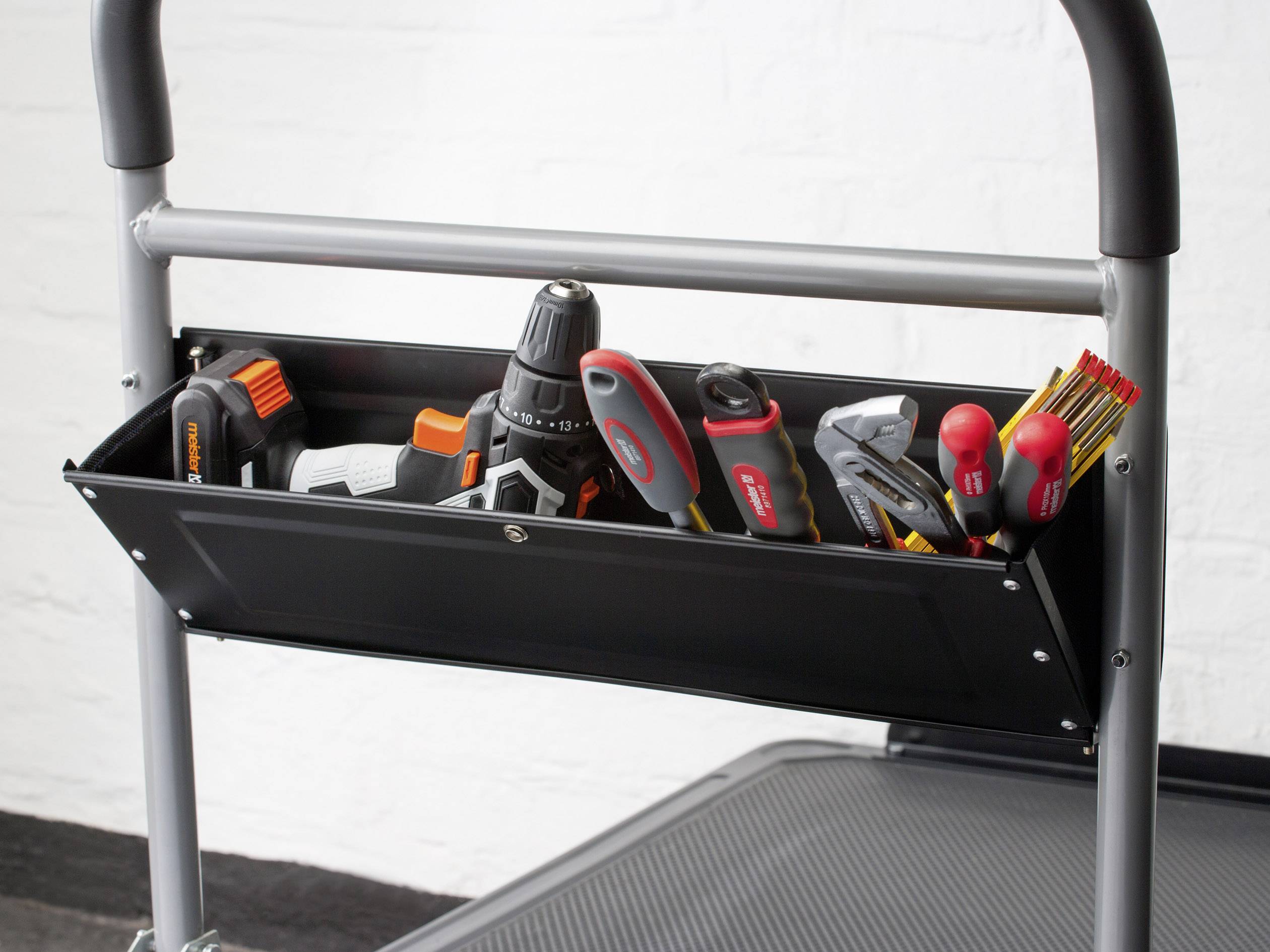 Czarna skrzynka narzędziowa na rusztowaniu zawiera różne narzędzia, takie jak wiertła, śrubokręty i nóż.