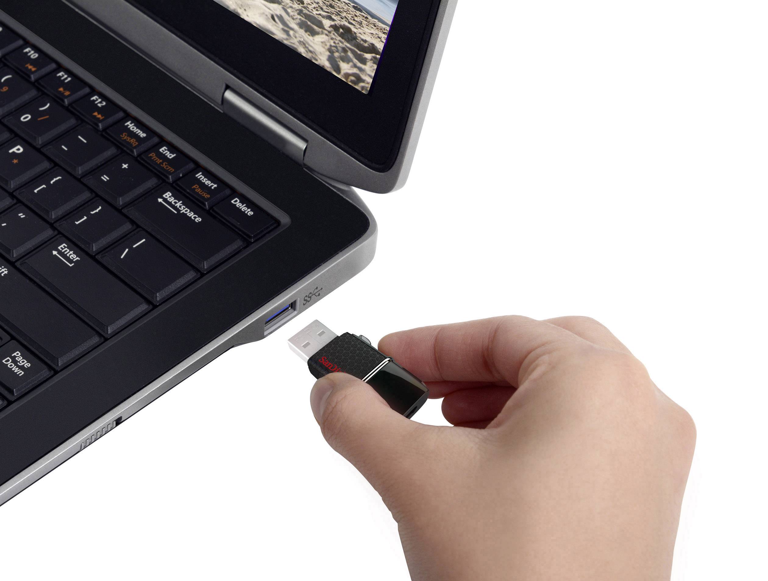 Ręka wkłada pendrive do laptopa, na którego ekranie wyświetlane są zdjęcia z plaży.
