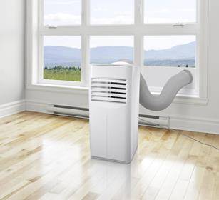 Przenośny wentylator klimatyzacyjny z przewodem odprowadzającym stoi w pustym pokoju z drewnianą podłogą, przed dużym oknem z widokiem na krajobraz.