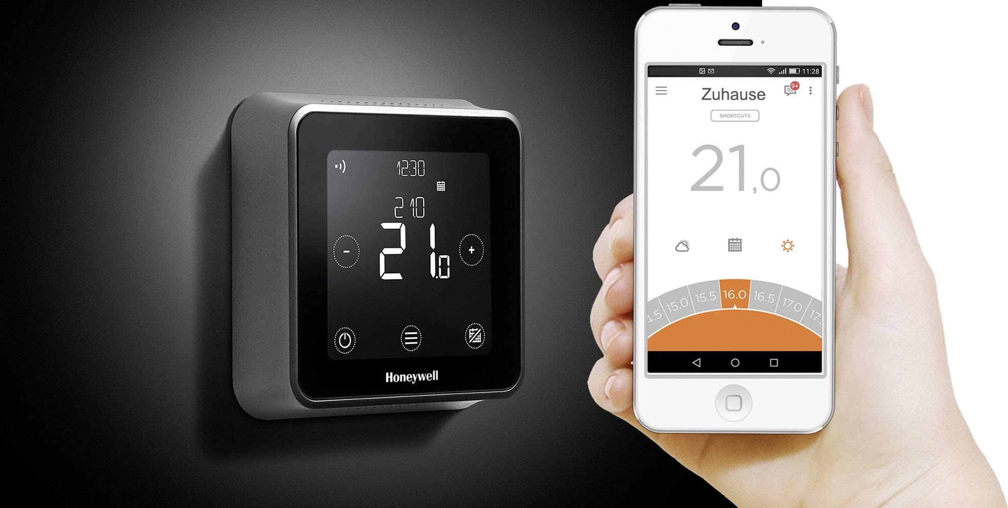 Inteligentny termostat na ścianie wskazuje 21 stopni. Obok, ręka trzyma smartfon z aplikacją wyświetlającą tę samą temperaturę.