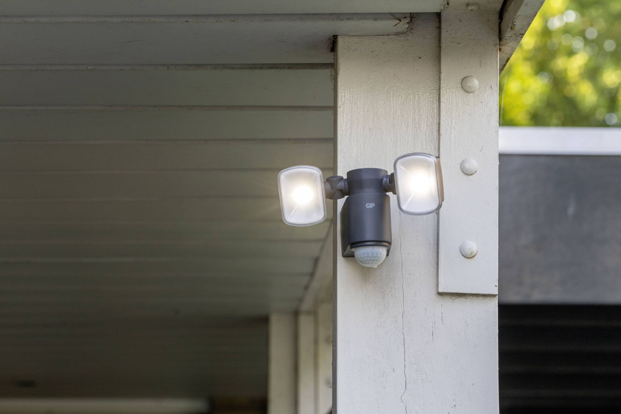 Lampa zewnętrzna z czujnikiem ruchu zamontowana na słupie, świecąca dwoma światłami o zmierzchu.