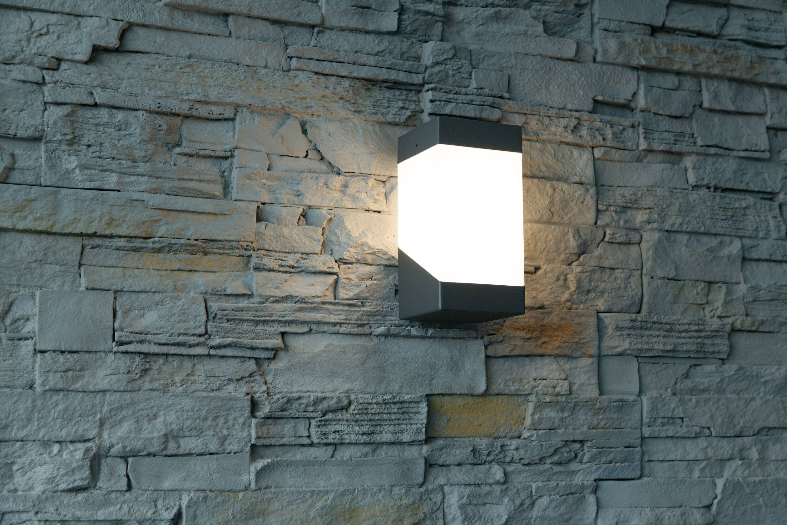 Nowoczesna, świecąca lampa ścienna na strukturalnej kamiennej ścianie.