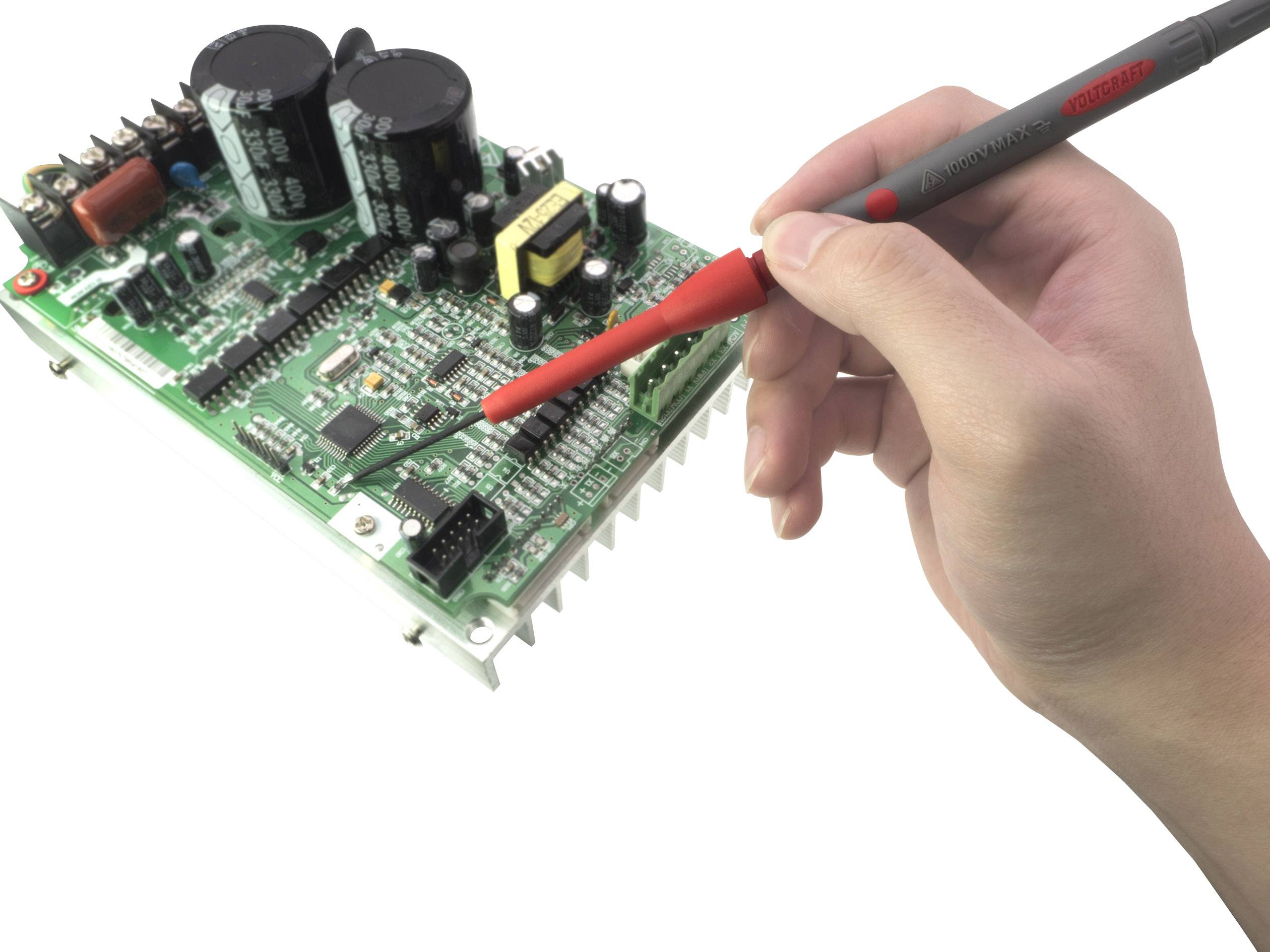 Jedna ręka trzyma urządzenie pomiarowe i pracuje nad zieloną płytką drukowaną z różnymi elementami elektronicznymi i obwodami.