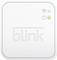 Biały hub systemu bezpieczeństwa Blink z dwoma diodami świecącymi w kolorach zielonym i niebieskim oraz stylizowanym symbolem Wi-Fi w prawym górnym rogu.
