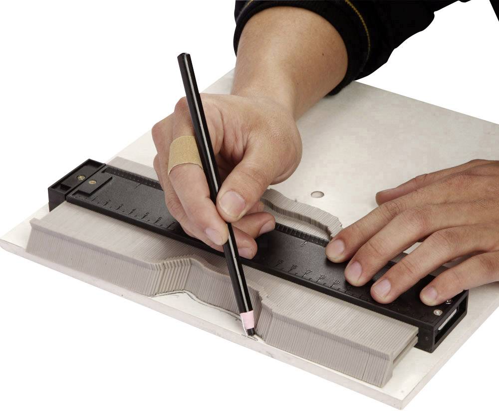 Osoba używa miernika konturów, aby odrysować kształt obiektu na kartce papieru ołówkiem.