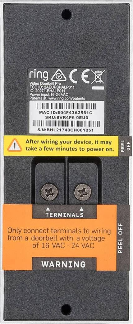 Czarne urządzenie z naklejkami; ostrzeżenie: "Podłączać wyłącznie z przewodowaniem dzwonka do drzwi 16-24 VAC." Górna część wskazuje dane techniczne.