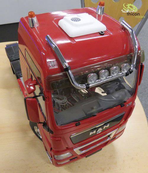 Czerwony model ciężarówki MAN na stole, widziany z góry. Samochód posiada szczegółowo wykonane światła i chromowane elementy.