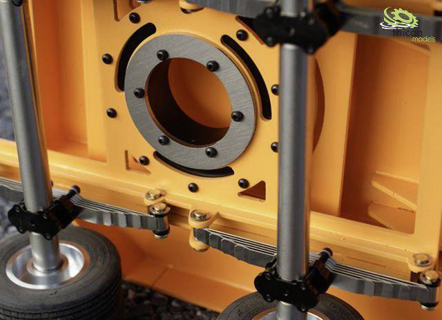 Zbliżenie pomarańczowego urządzenia z widocznym metalowym pierścieniem pośrodku i czterema kółkami u dołu. Funkcja nieznana.