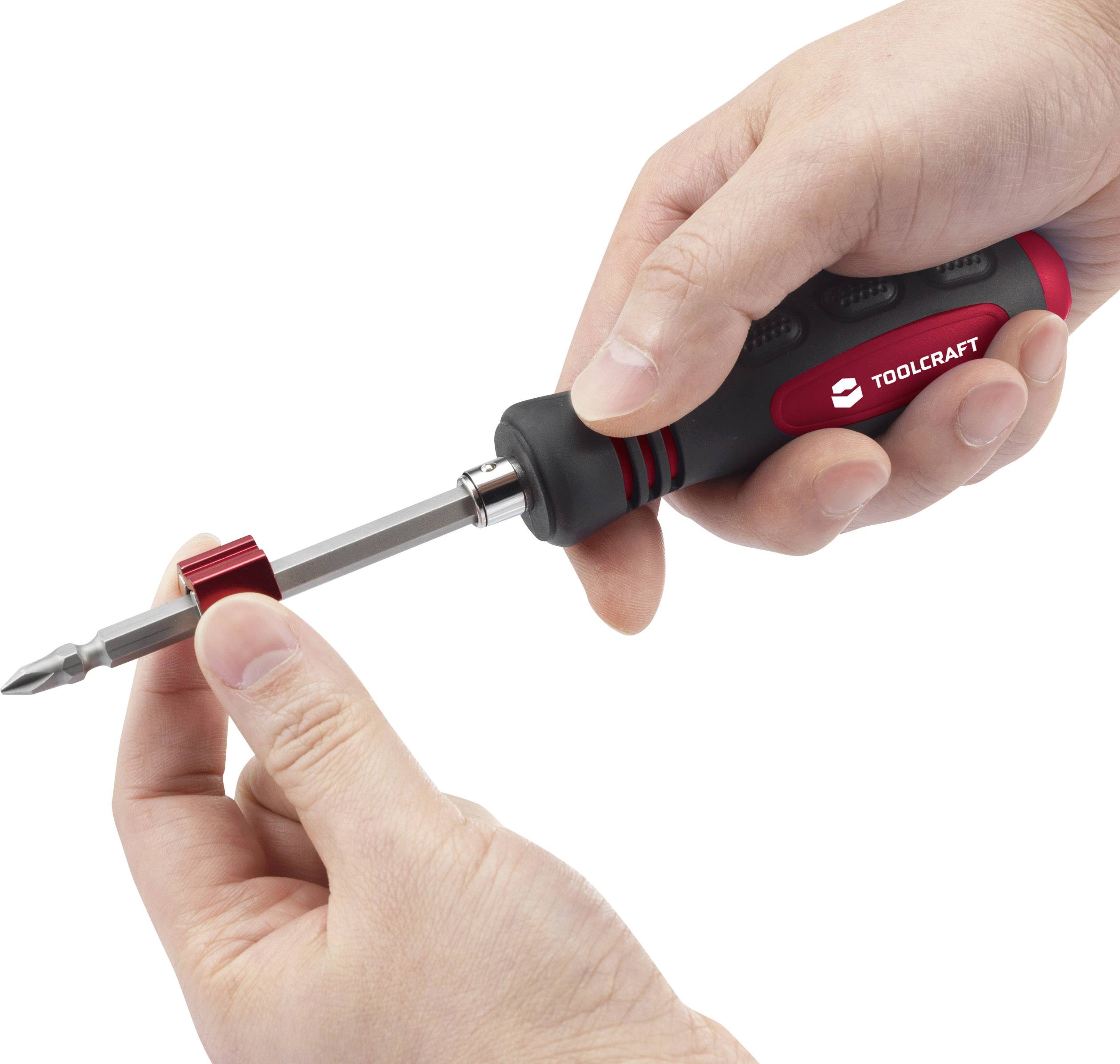 Dwie ręce trzymają wkrętak z uchwytem w kolorach czerwonym i czarnym, obejmujący końcówkę wkrętaka.
