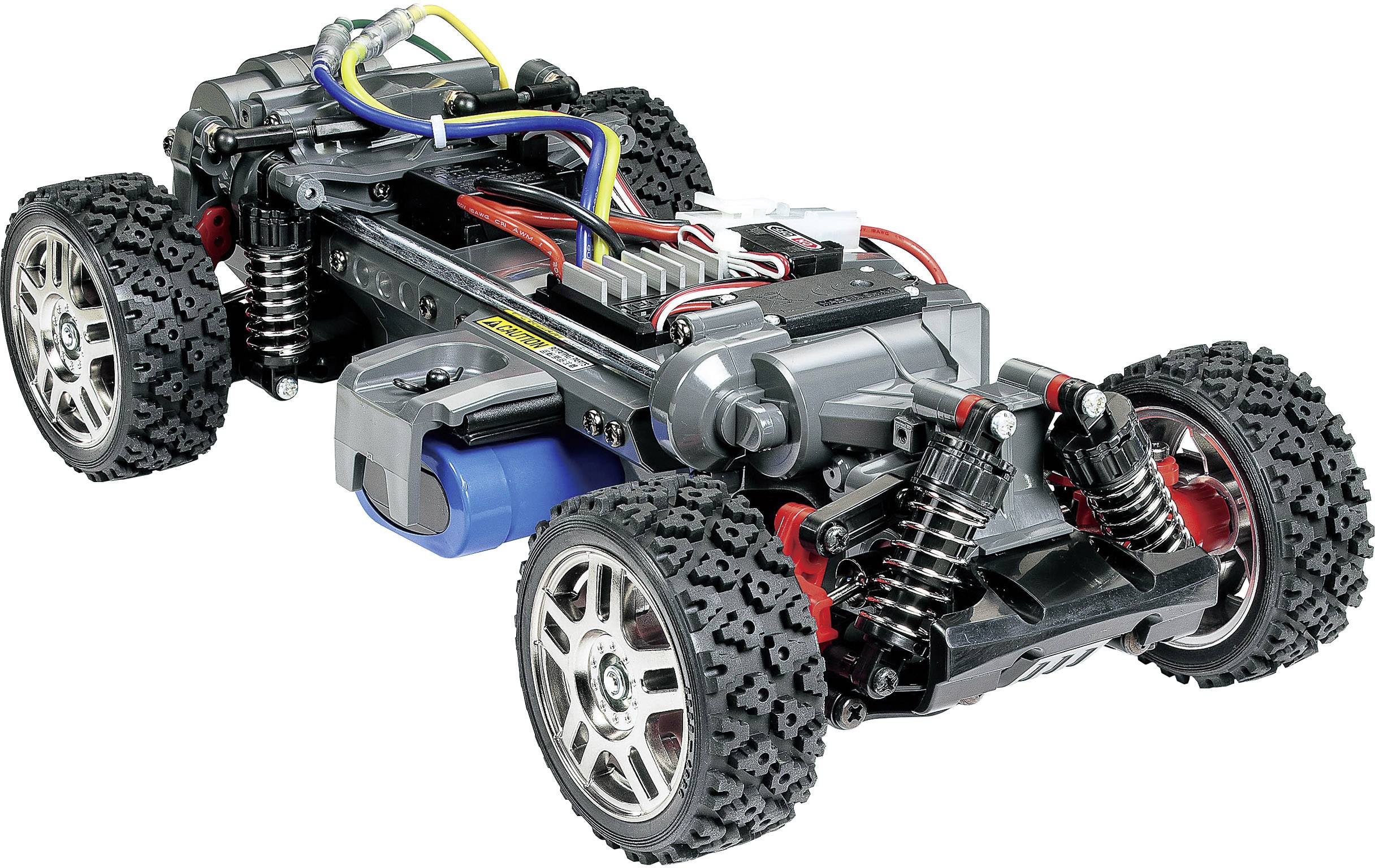 Zdalnie sterowane podwozie samochodu z widocznymi komponentami, takimi jak koła, sprężyny, przewody i silnik, na białym tle.