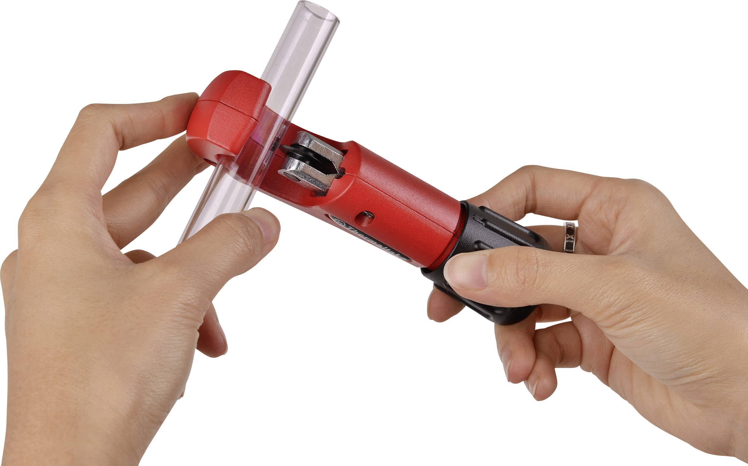 Ręce używają czerwonego obcinaka do rur, aby przeciąć przezroczystą rurę.