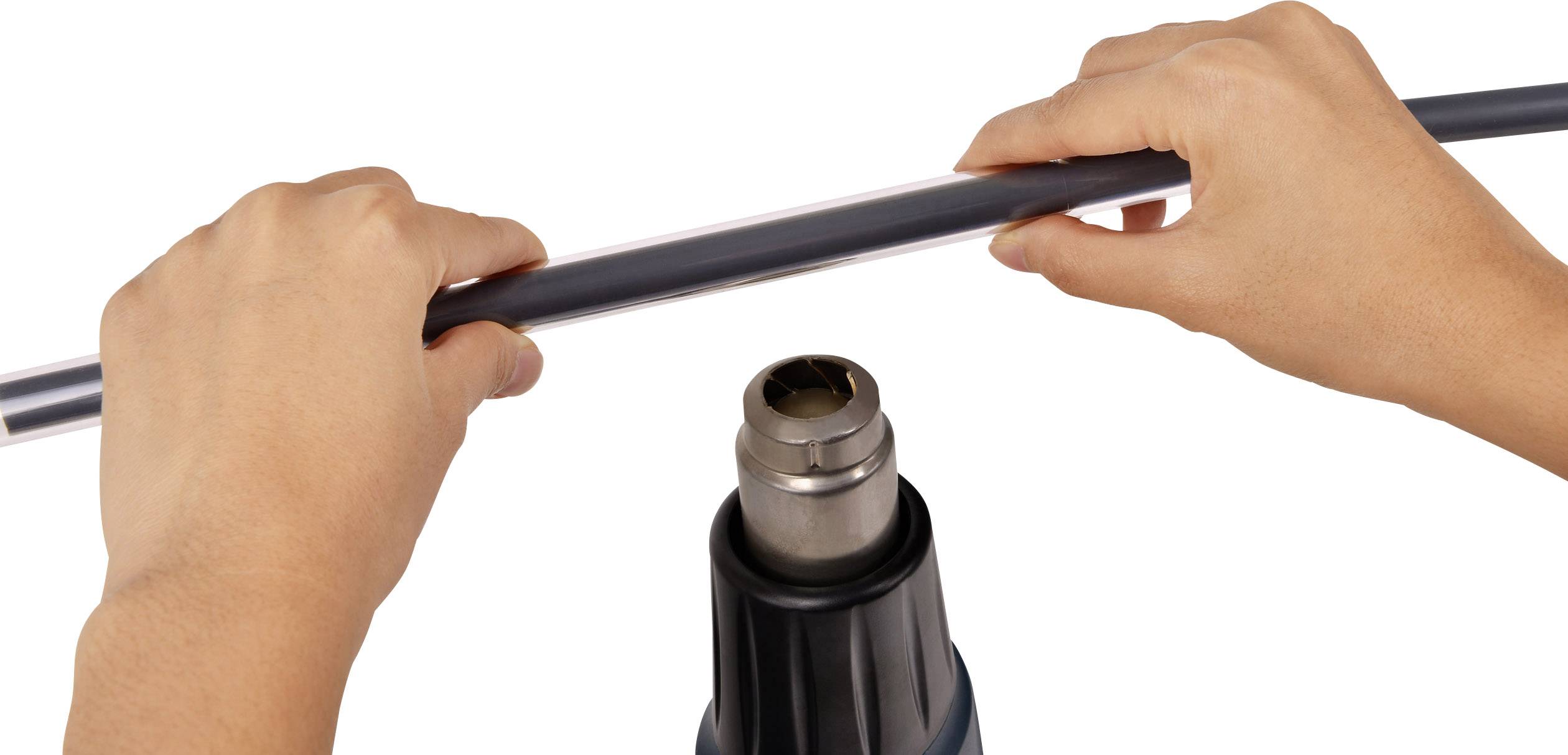 Osoba trzyma długą, ciemną rurę nad suszarką do włosów. Rura jest podgrzewana, aby stała się plastyczna.