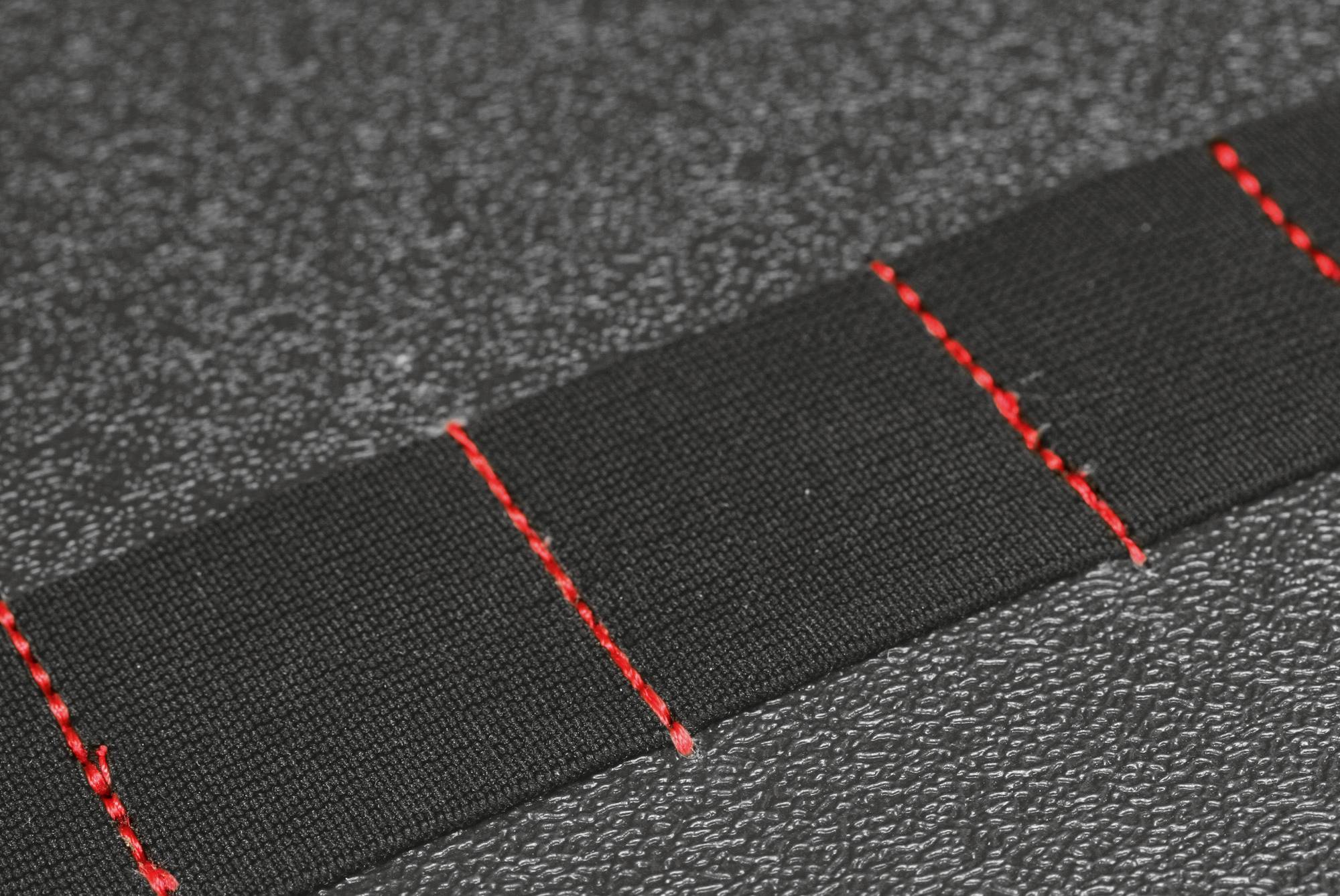 Czarna wstążka z czerwonymi szwami, spoczywająca na strukturalnym szarym tle, podkreśla dbałość o szczegóły w tkaninie.