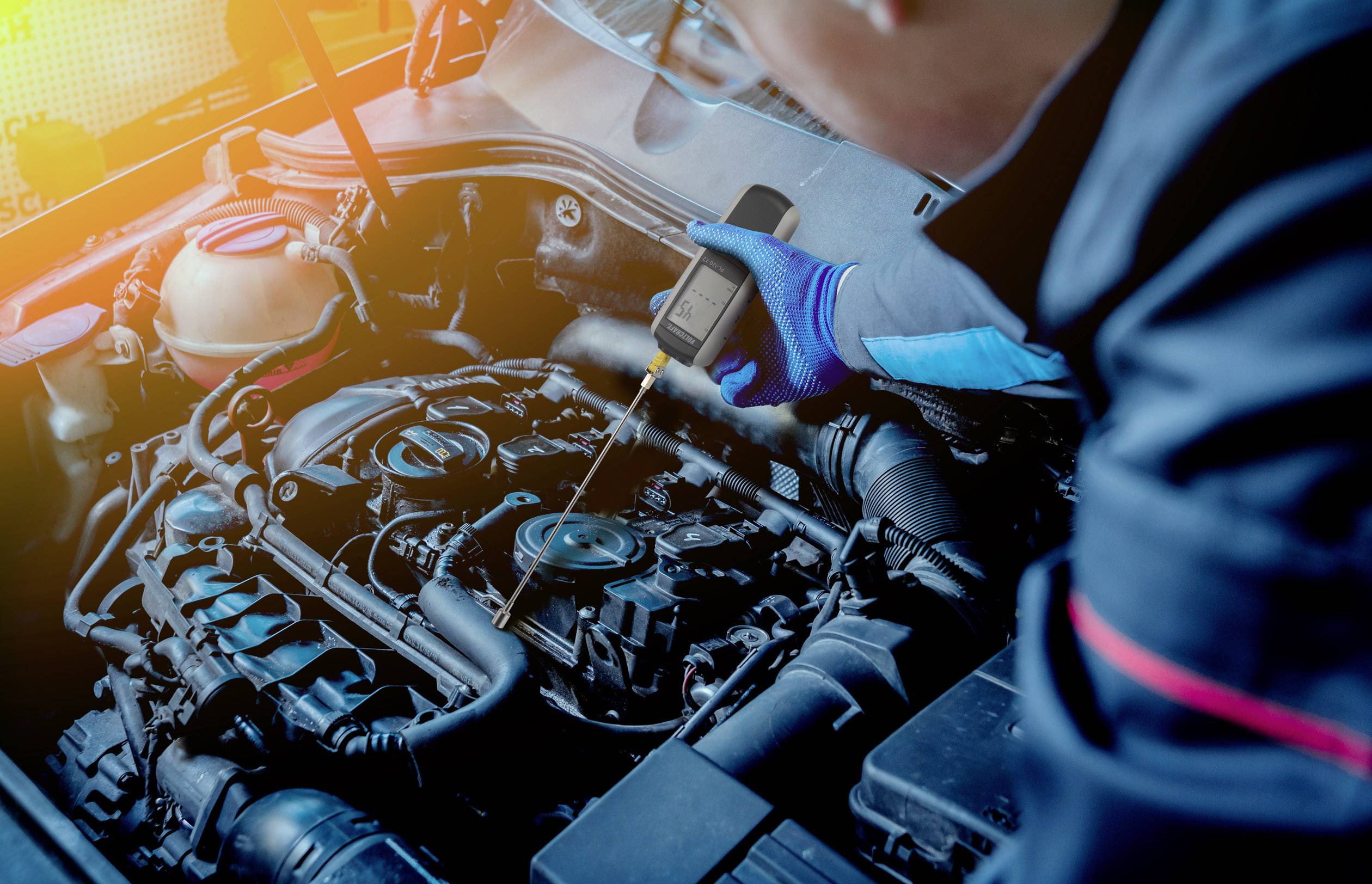 Mechanik sprawdza silnik samochodu za pomocą urządzenia diagnostycznego. Komora silnika jest wyraźnie widoczna, a nacisk położony jest na diagnostyce.