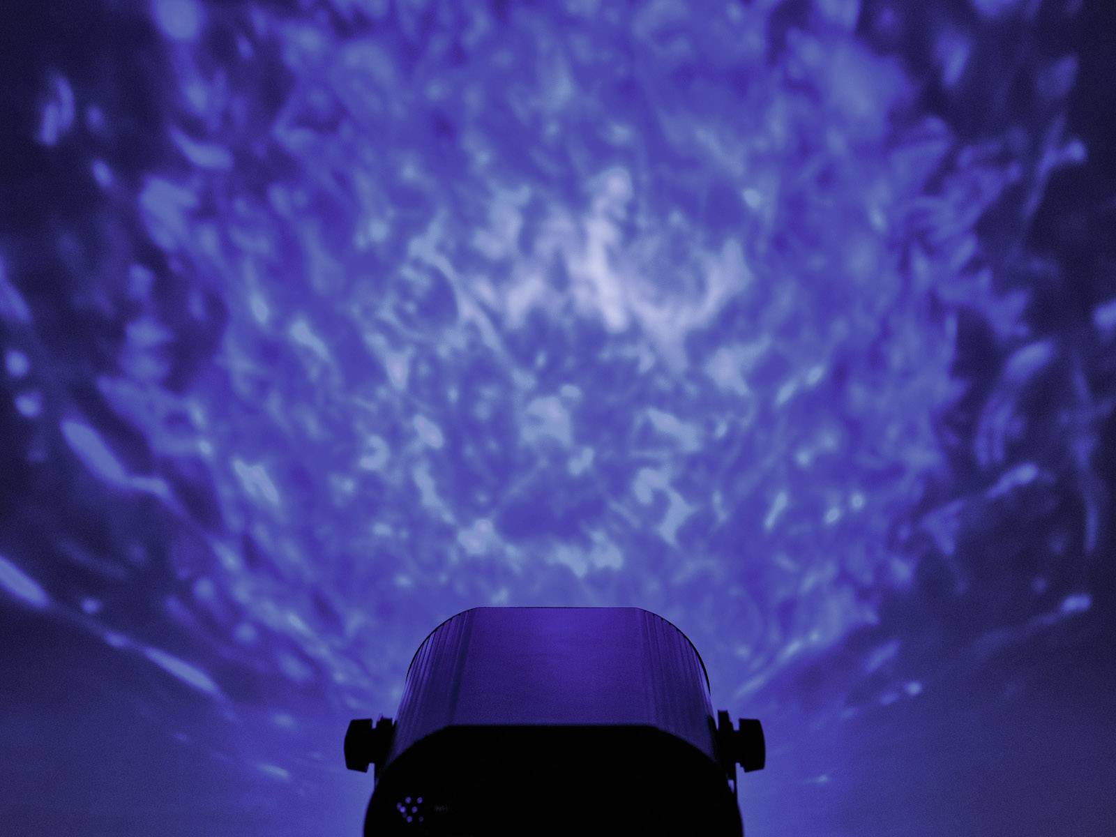 Projektor rzuca na sufit niebieskie, wirujące wzory, które tworzą iluzoryczną, niemal niebiańską atmosferę.