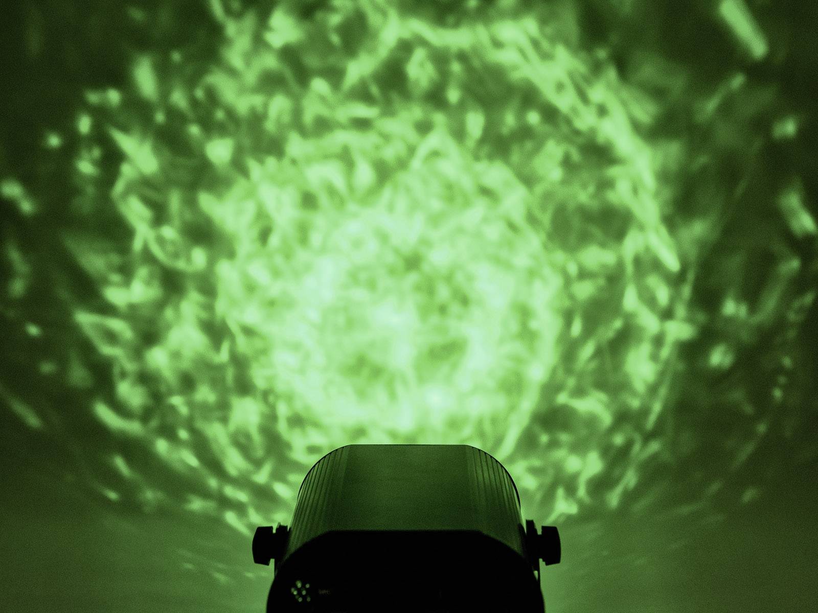 Reflektor rzuca na ścianę zielony, wirujący wzór przypominający odbicia wody.