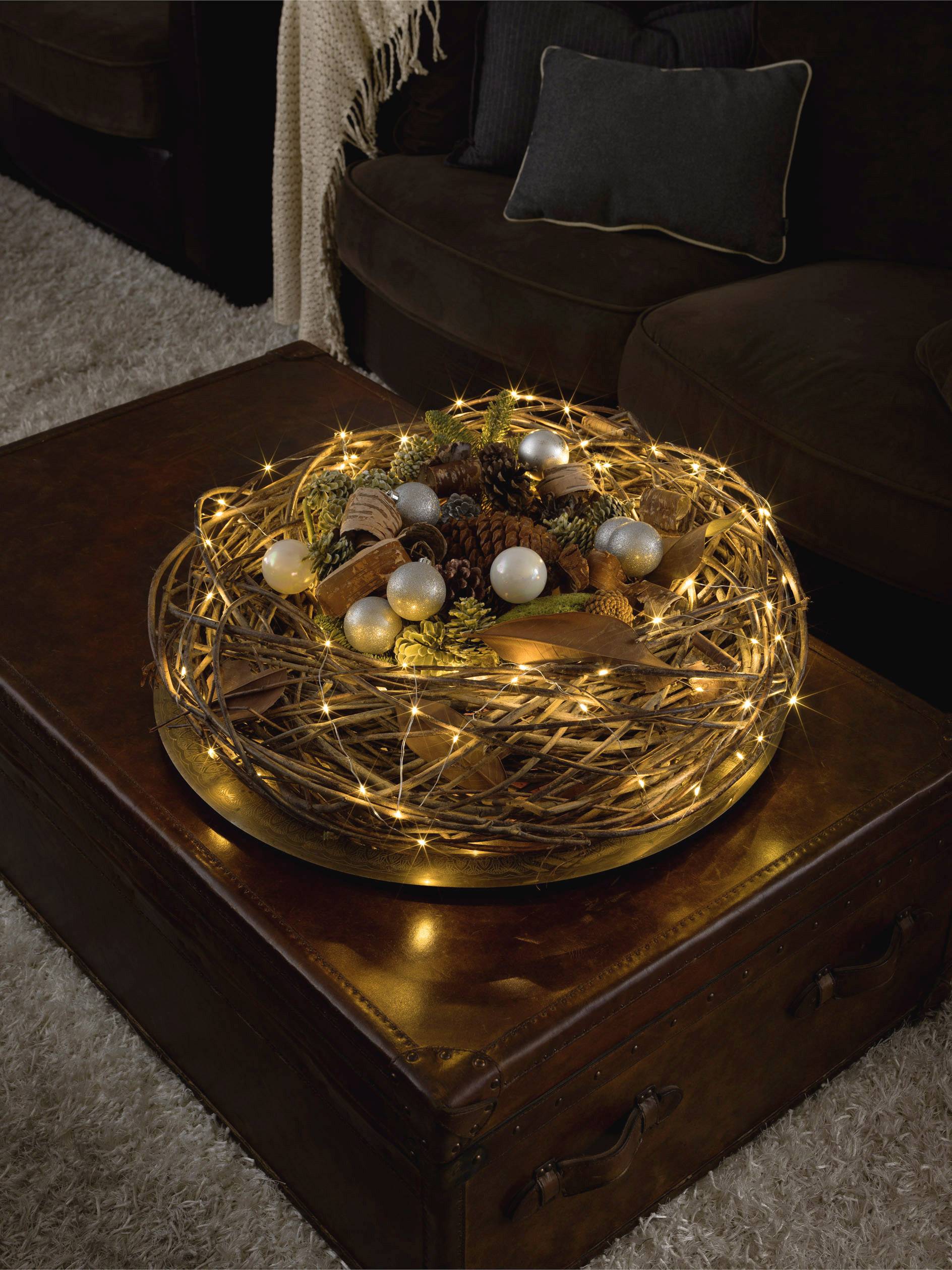 Kosz na stole, wypełniony jesiennymi dekoracjami i girlandami świetlnymi, tworzy przytulną atmosferę w pomieszczeniu mieszkalnym.