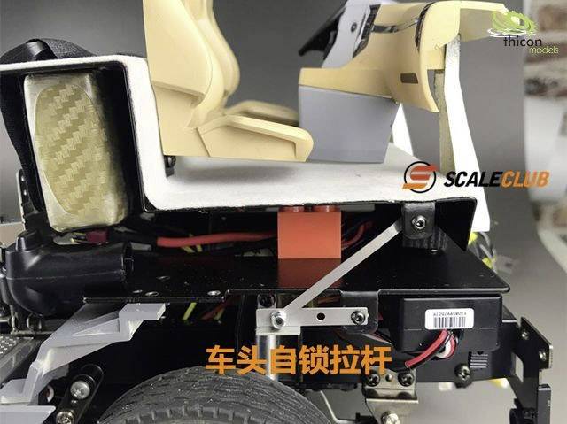 Model wnętrza samochodu z siedzeniami i deską rozdzielczą, widoczne szczegóły elektroniki i okablowania, logo marki w prawym górnym rogu.