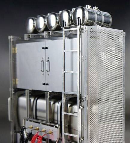 Przemysłowy pojemnik metalowy z wieloma komorami cylindrycznymi i kratkami, odpowiedni do zastosowań technicznych lub przemysłowych.