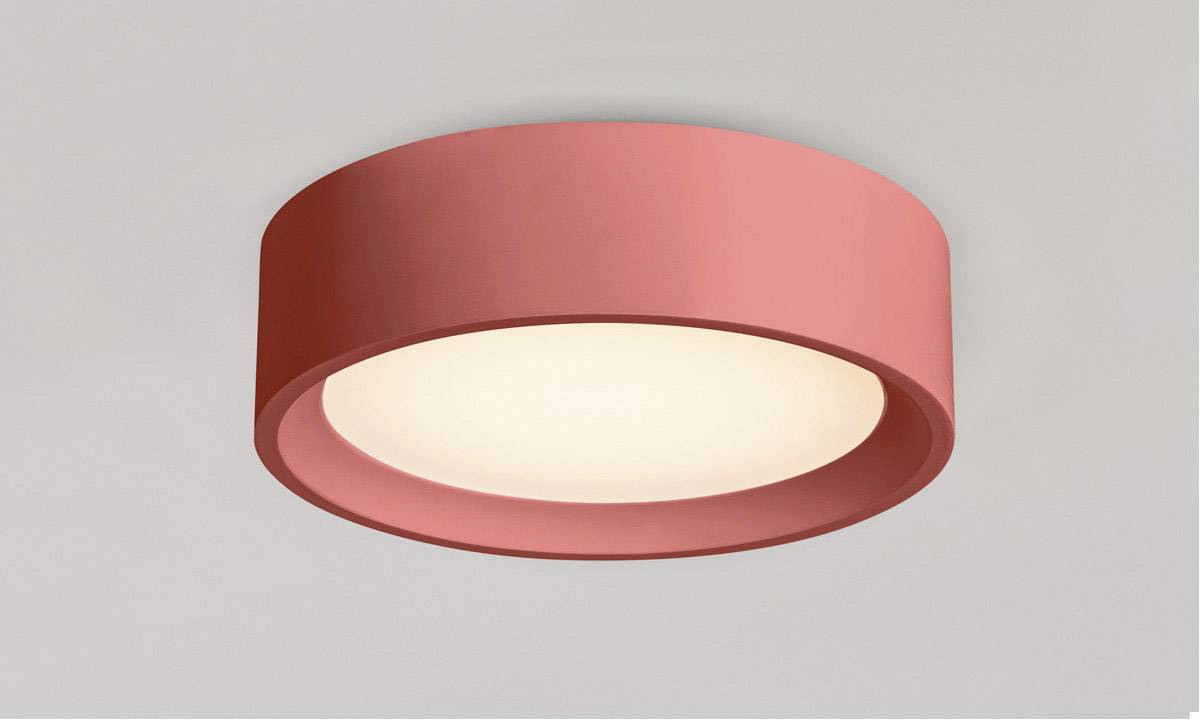 Czerwona lampa sufitowa o okrągłym kształcie, emitująca ciepłe białe światło. Zamocowana na szarym suficie. O nowoczesnym i minimalistycznym wyglądzie.
