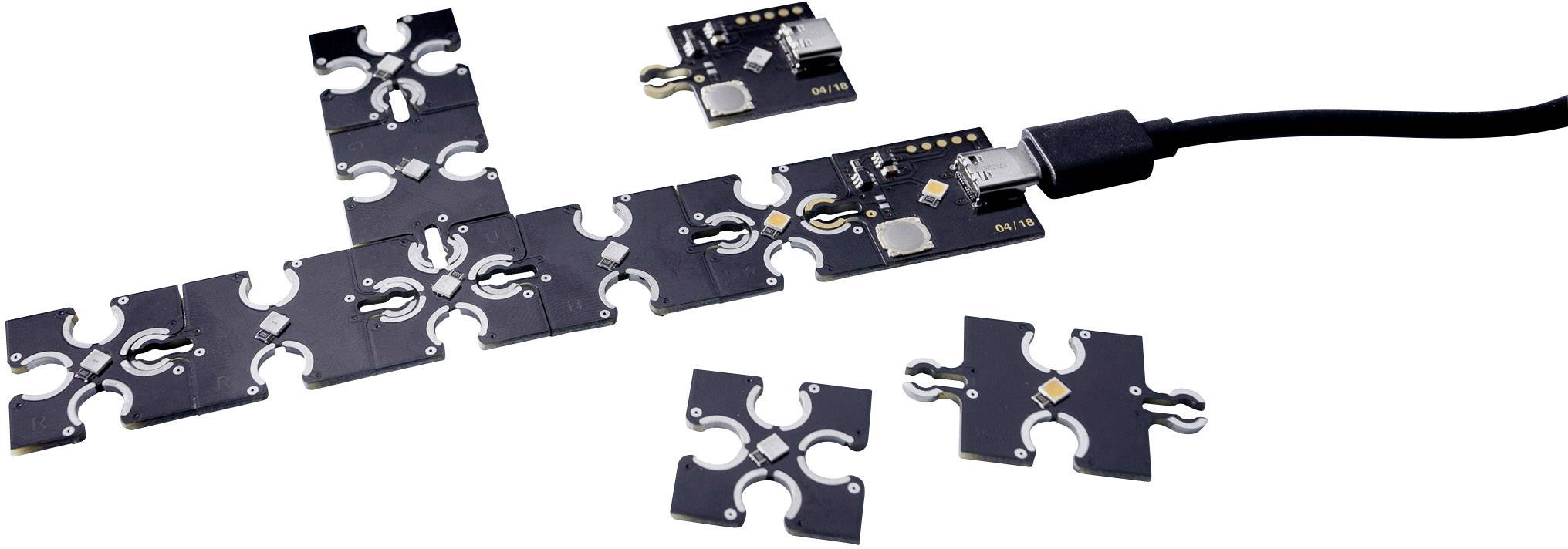 Kwadratowe, przypominające puzzle elektroniczne moduły są połączone kablem USB. Niektóre moduły są rozłączone.