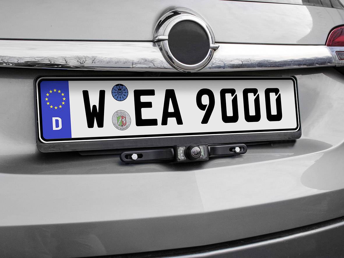 Polska tablica rejestracyjna z numerem 'W EA 9000' na srebrnym pojeździe, widoczna flaga UE i naklejka TÜV.