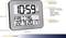 Cyfrowy zegar radiowy z dużym wyświetlaczem, pokazujący godzinę, dzień tygodnia i datę. Tekst dostępny w różnych językach. Wymiary: 258x212x30 mm.