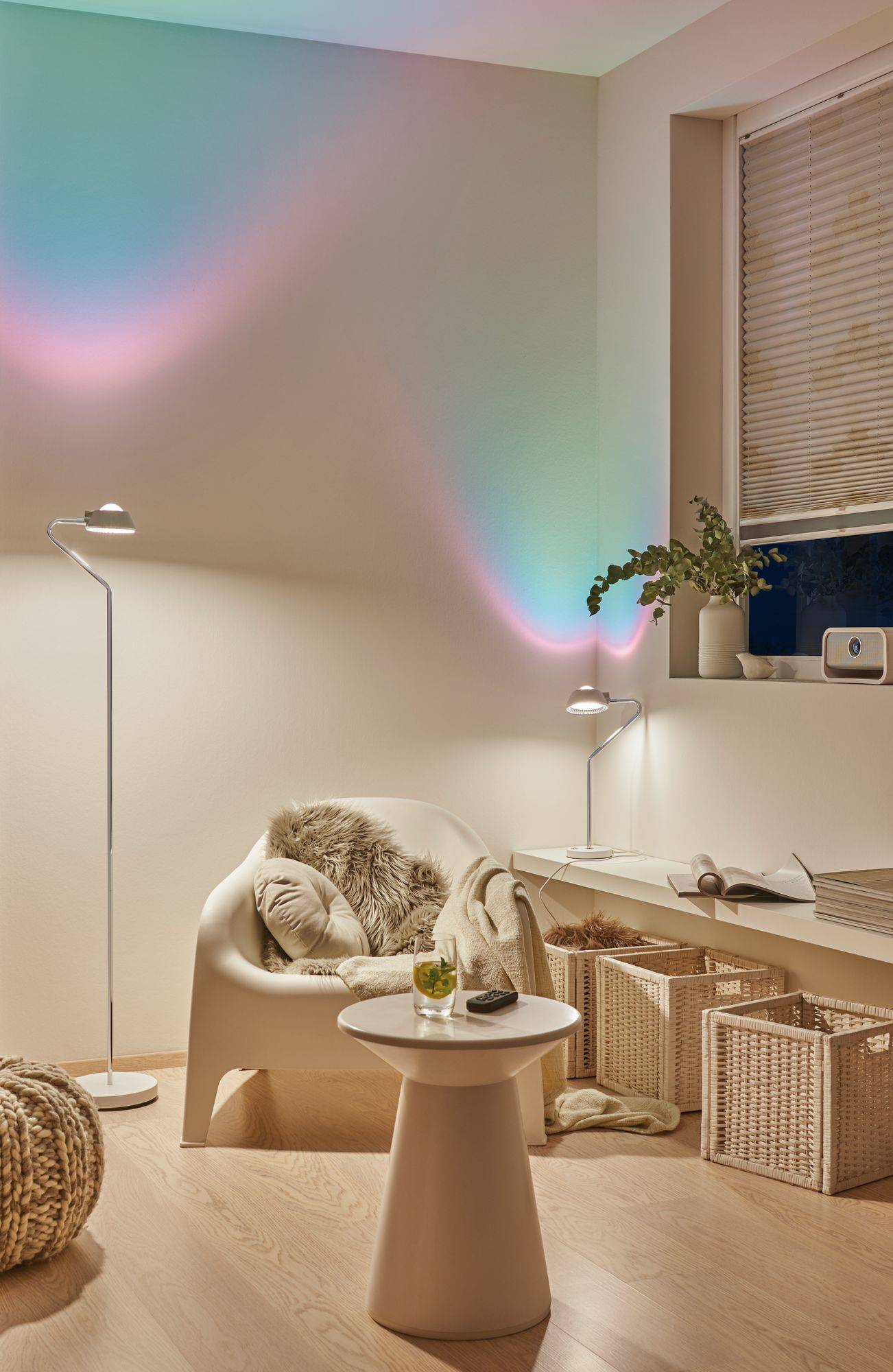 Przytulnie urządzony salon z fotelem, stolikiem pomocniczym, dekoracyjnymi efektami świetlnymi na ścianie i roślinami na regale.