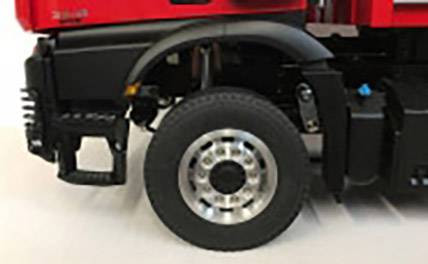 Czerwony pojazd, zbliżenie lewego przedniego koła i błotnika, prawdopodobnie używany do transportu lub budowy.